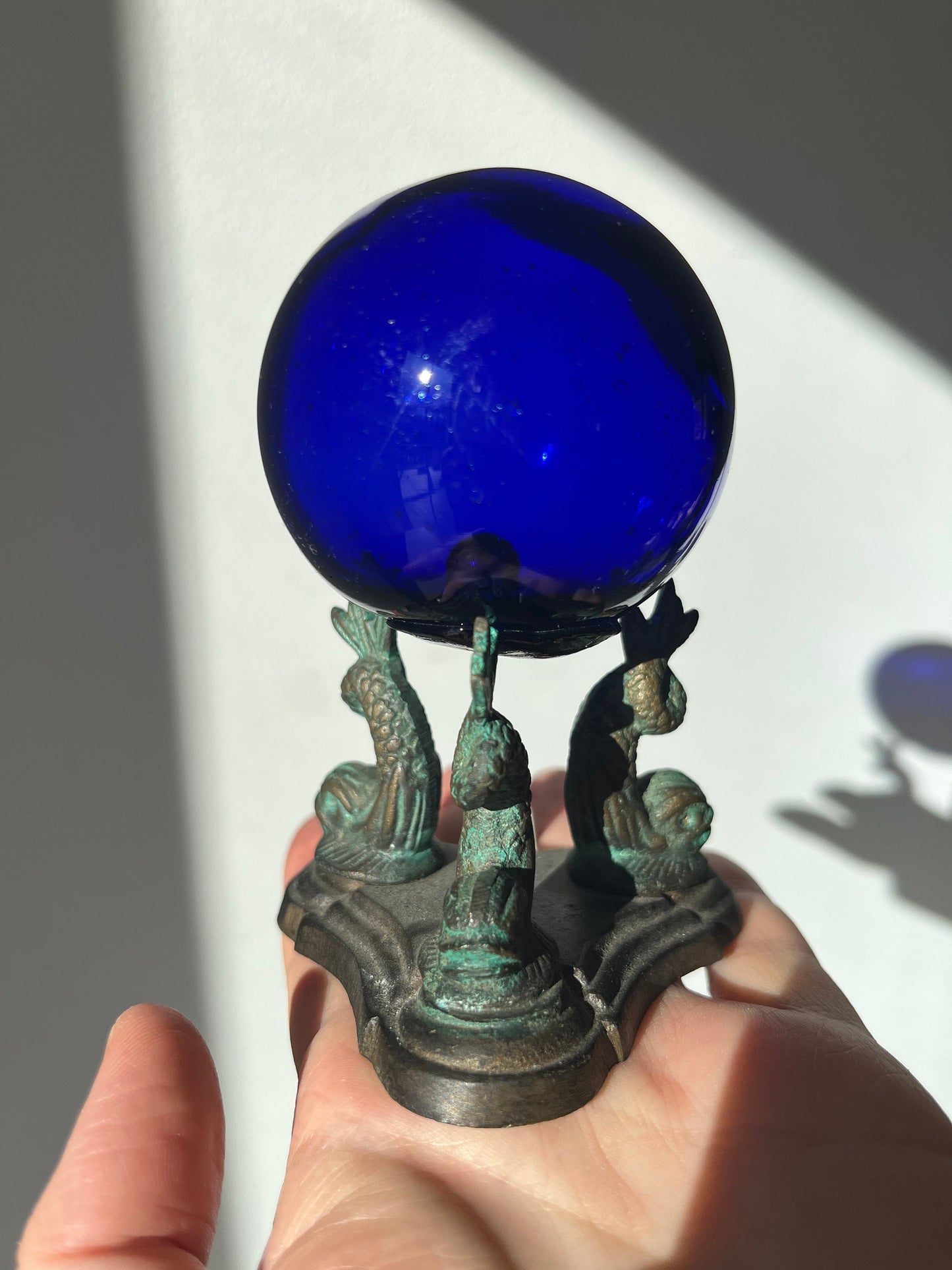 Vintage cobalt blue glass ball on a metal fish sculpture stand