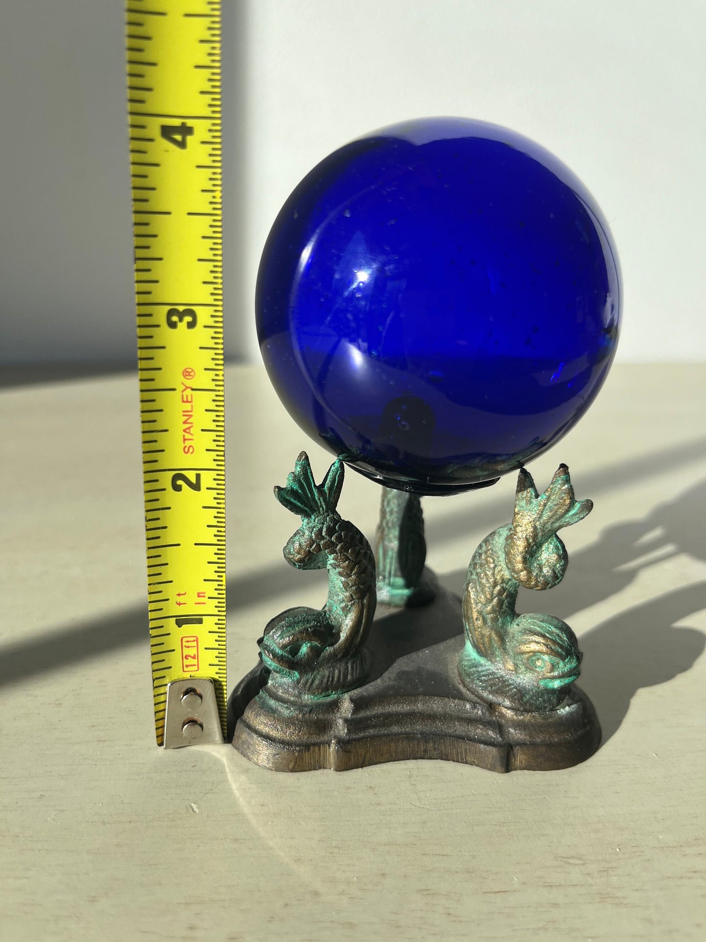 Vintage cobalt blue glass ball on a metal fish sculpture stand