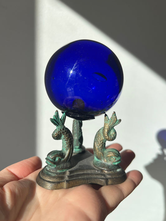 Vintage cobalt blue glass ball on a metal fish sculpture stand
