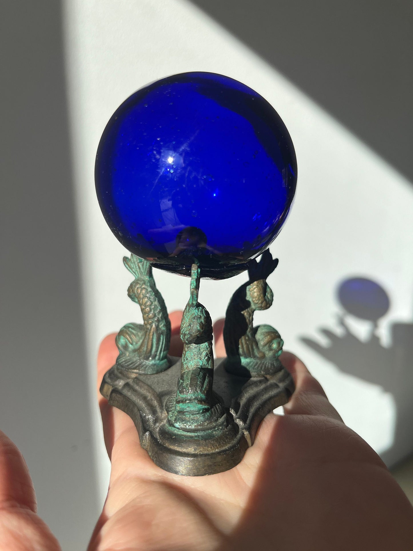 Vintage cobalt blue glass ball on a metal fish sculpture stand