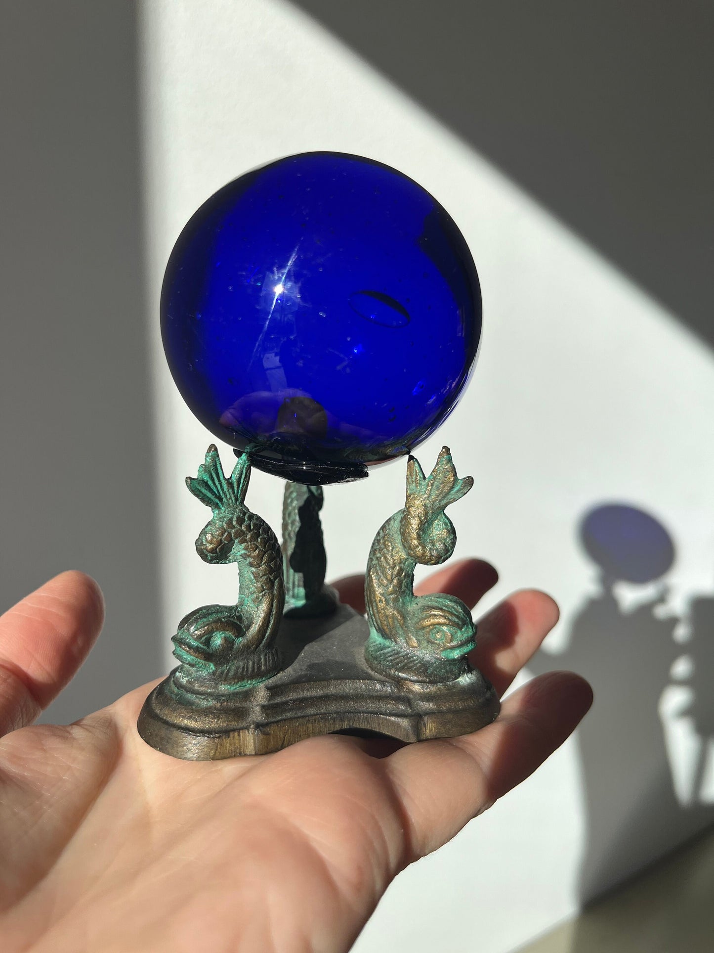 Vintage cobalt blue glass ball on a metal fish sculpture stand