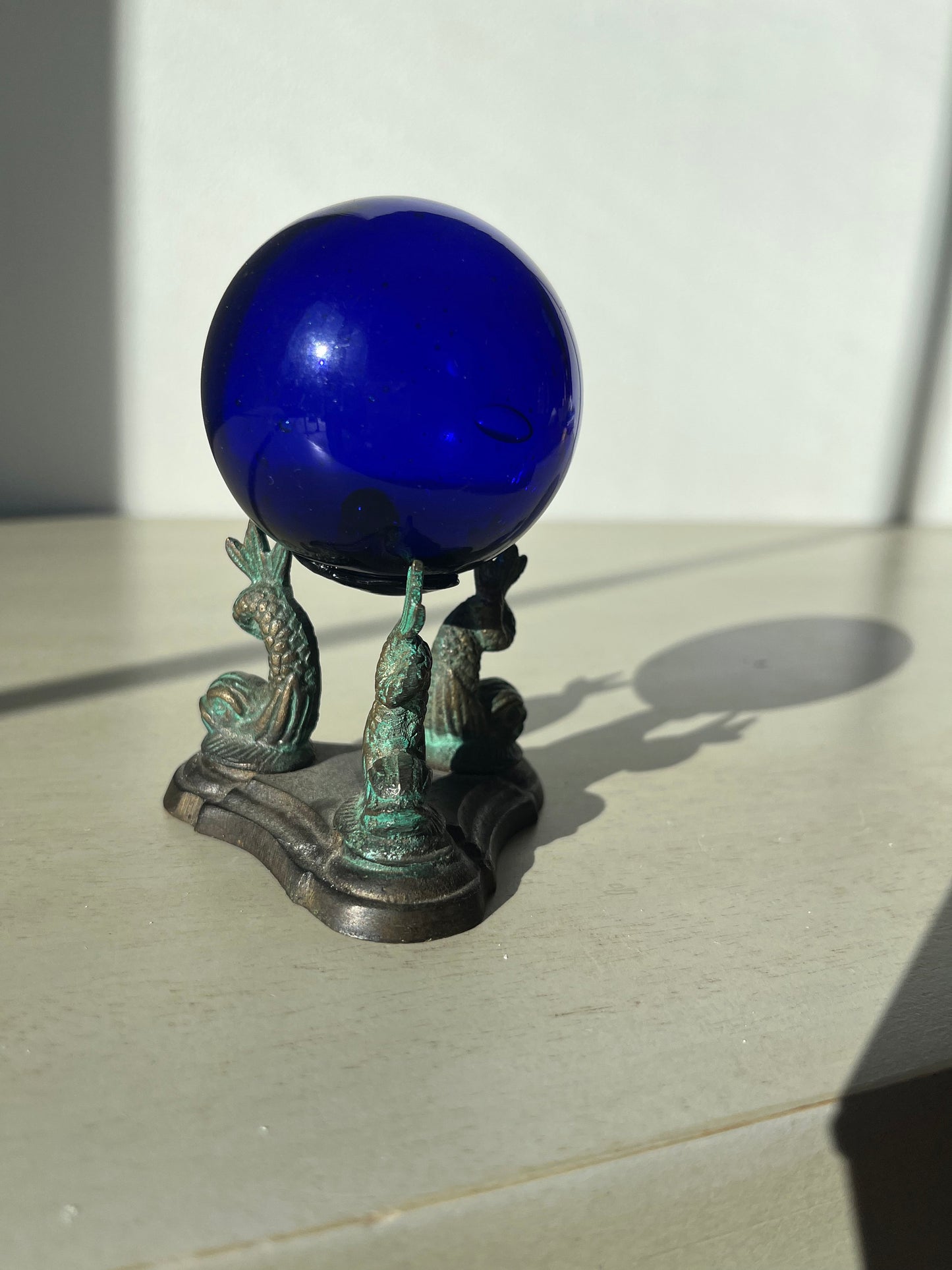Vintage cobalt blue glass ball on a metal fish sculpture stand